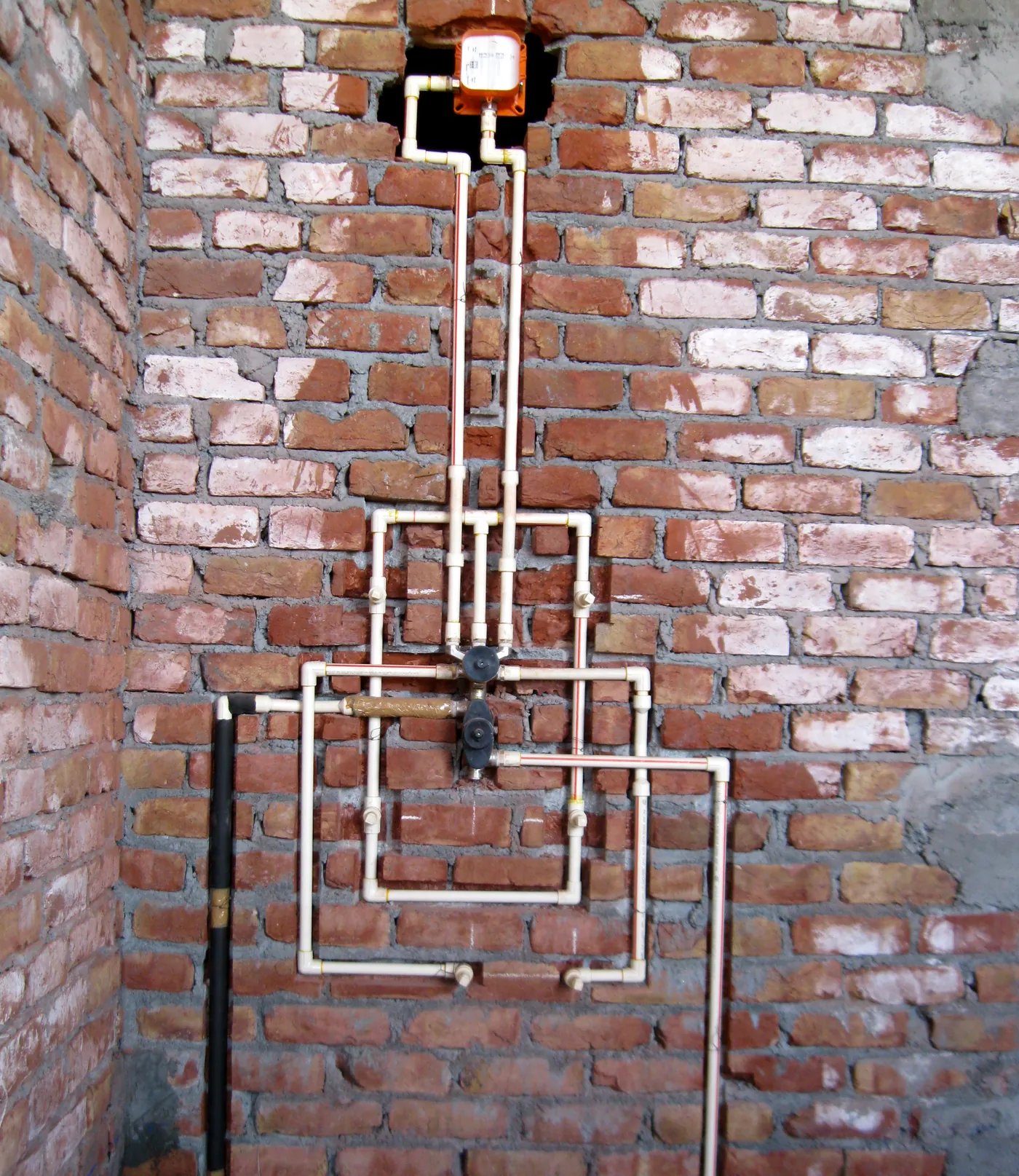 Concealed shower lines before tiling: a mixer valve at the centre, a loop for four body jets, the rain-shower outlet at the top and plugged outlets for the spout and hand shower